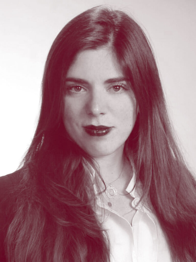 In primo piano Haydèe Longo, una donna con i capelli lunghi fino alle spalle, una camicia bianca e una giacca scura.