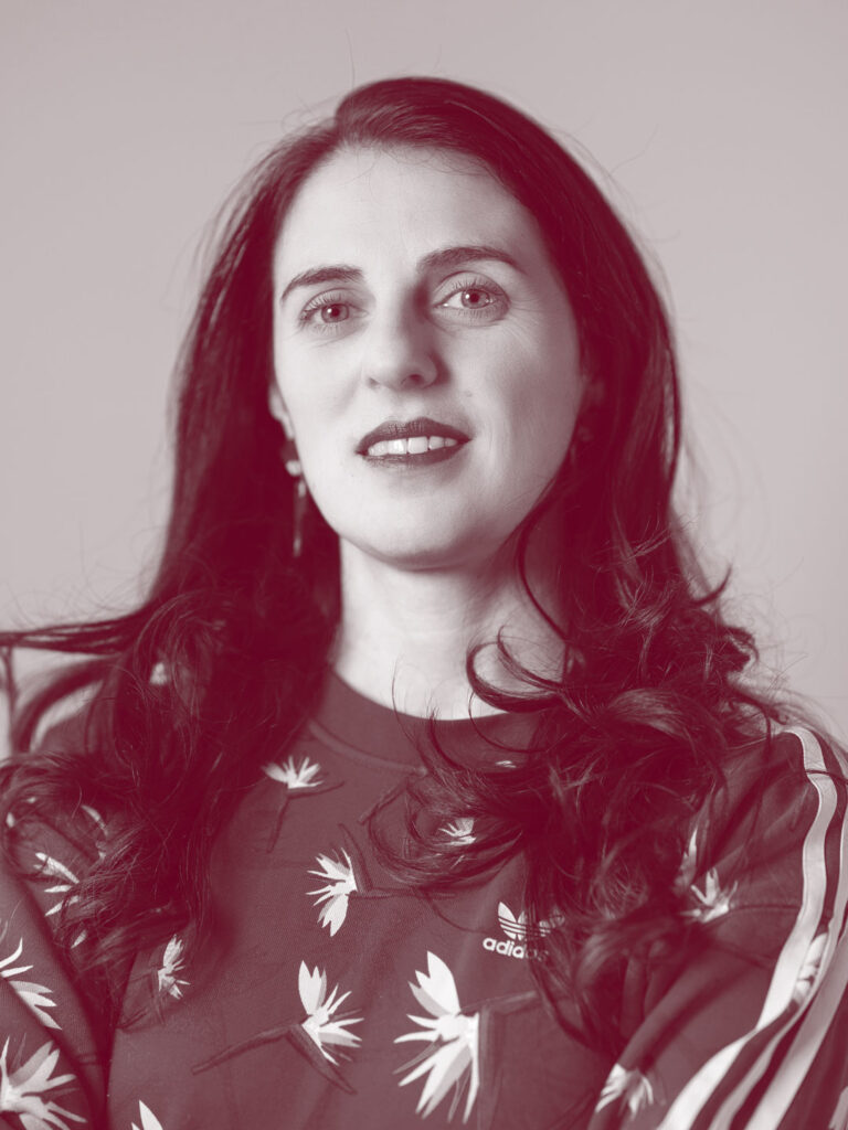 In primo piano Simona Martini, una persona con i capelli scuri, lunghi e sciolti. Indossa una felpa.
