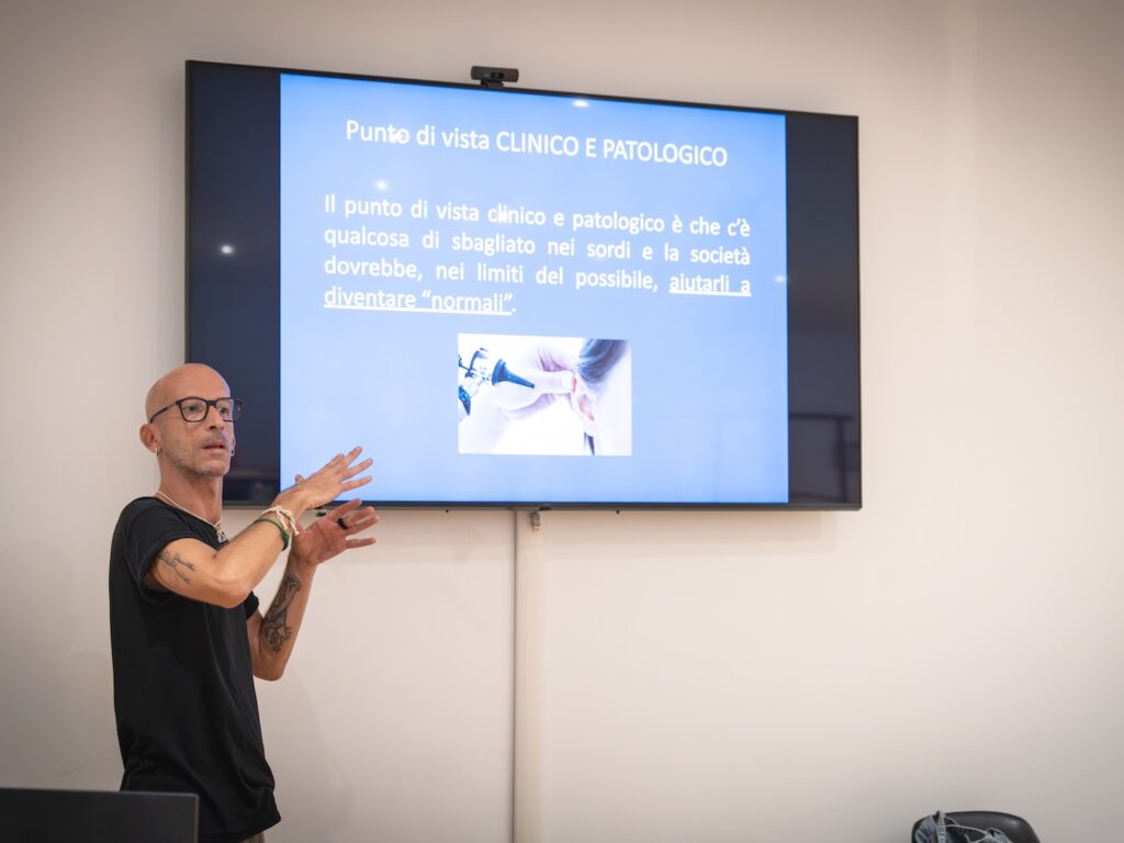 Foto scattata durante la formazione. Il docente, in piedi di accanto allo schermo, si rivolge al pubblico. Foto di Marta Cervone.